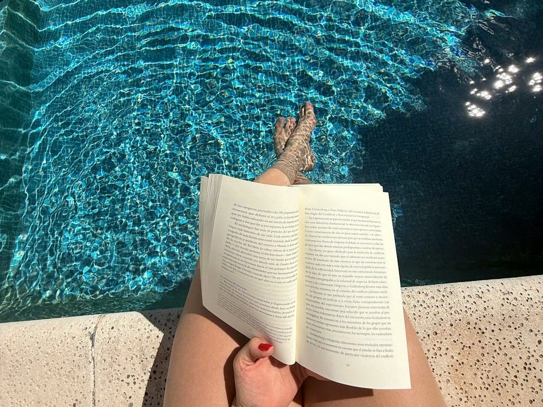 Person reading a book by the swimming pool Person reading a book by the swimming pool