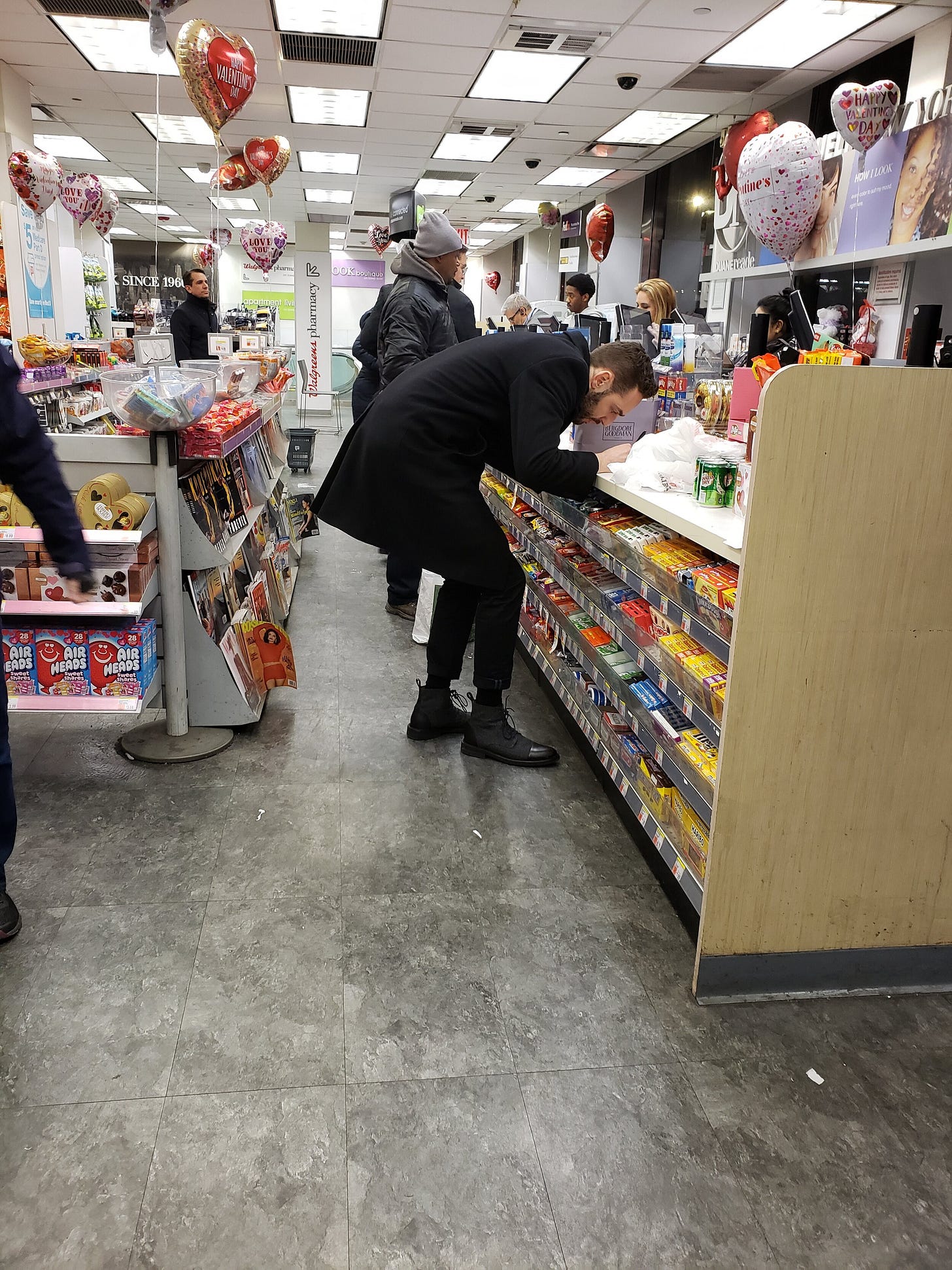 Pictured: A poor schmuck on Valentine’s Day in his natural habitat, frantically signing a Hallmark card using a pen from the register.