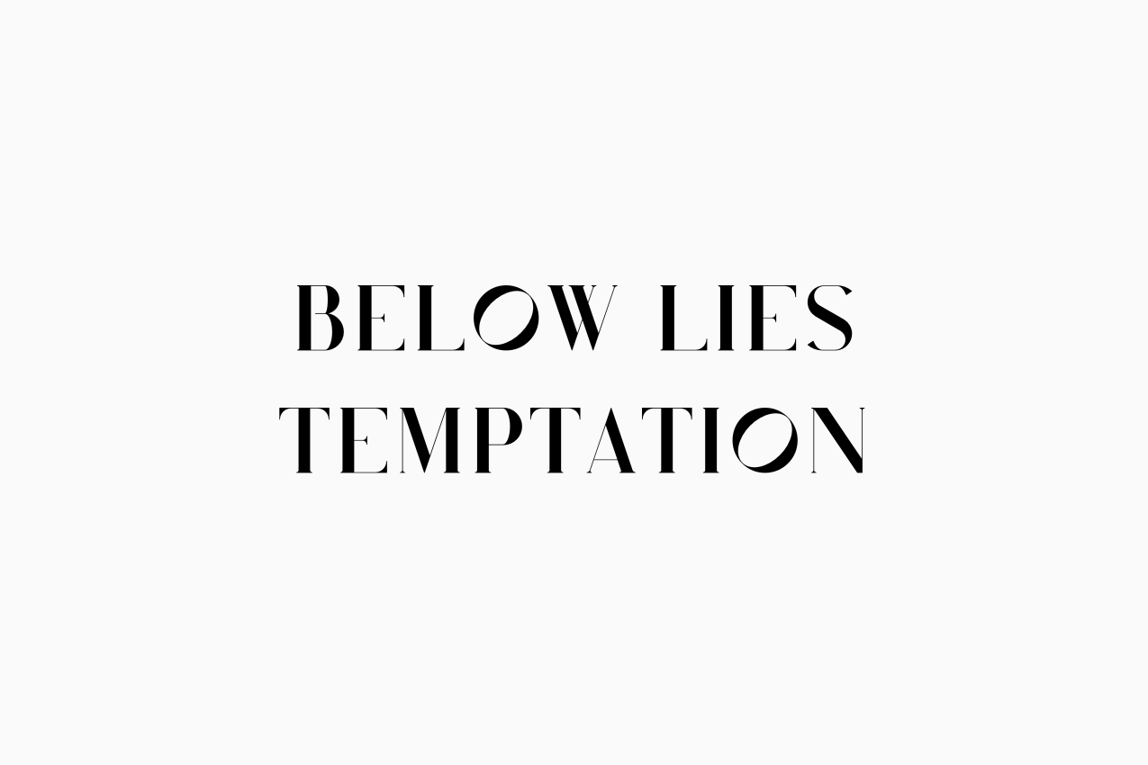 A minimalist visual divider featuring the words “BELOW LIES TEMPTATION” in a high-contrast serif typeface. The text serves as an editorial warning before the puzzle hints section.