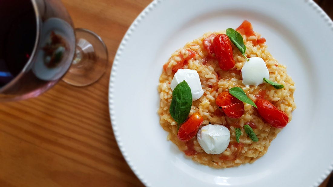 Foto do risoto caprese com uma taça de vinho.