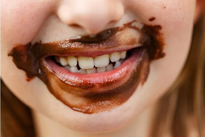 a little girl smiling with chocolate around her lips