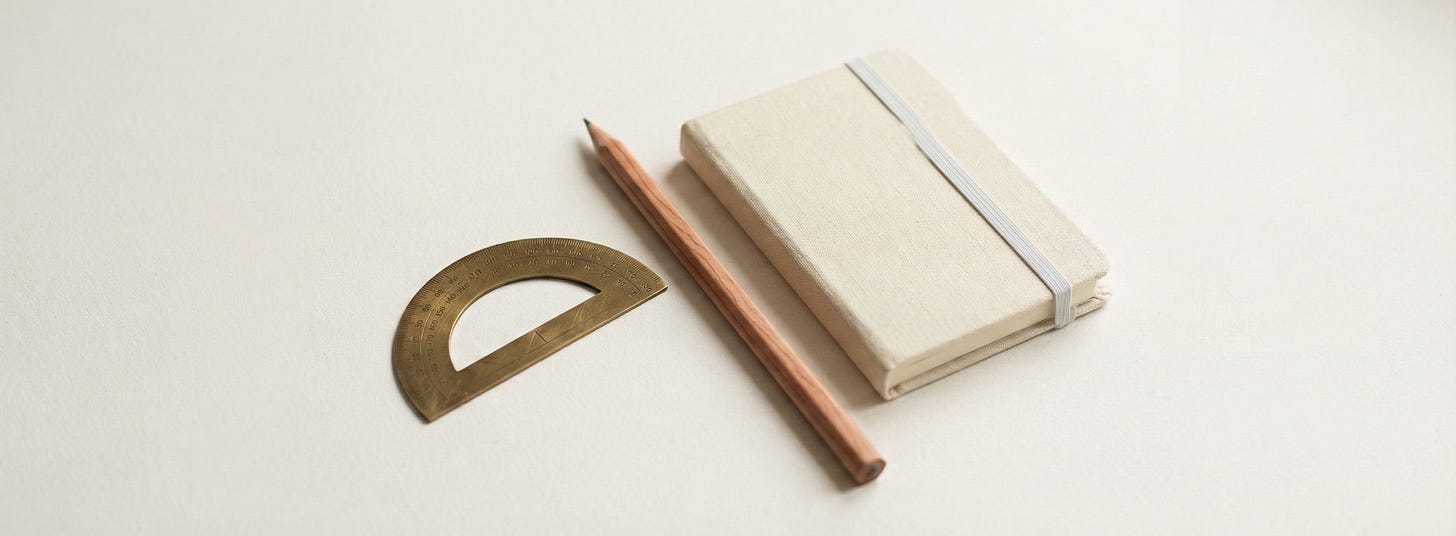 Brass protractor, wooden pencil, and cream linen notebook with elastic closure on minimal white surface