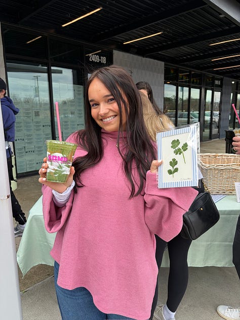 Lots of people holding a green smoothie at an in-person event for Grace & Greens