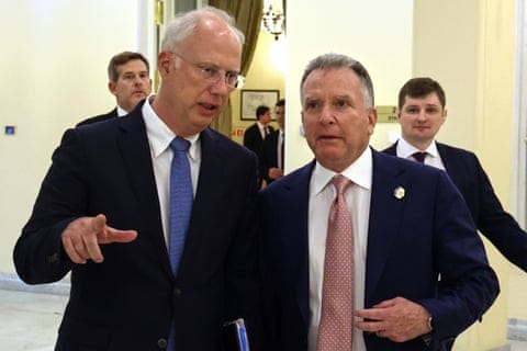 Kirill Dmitriev and Steve Witkoff walk down a corridor leaning in towards each other as they talk