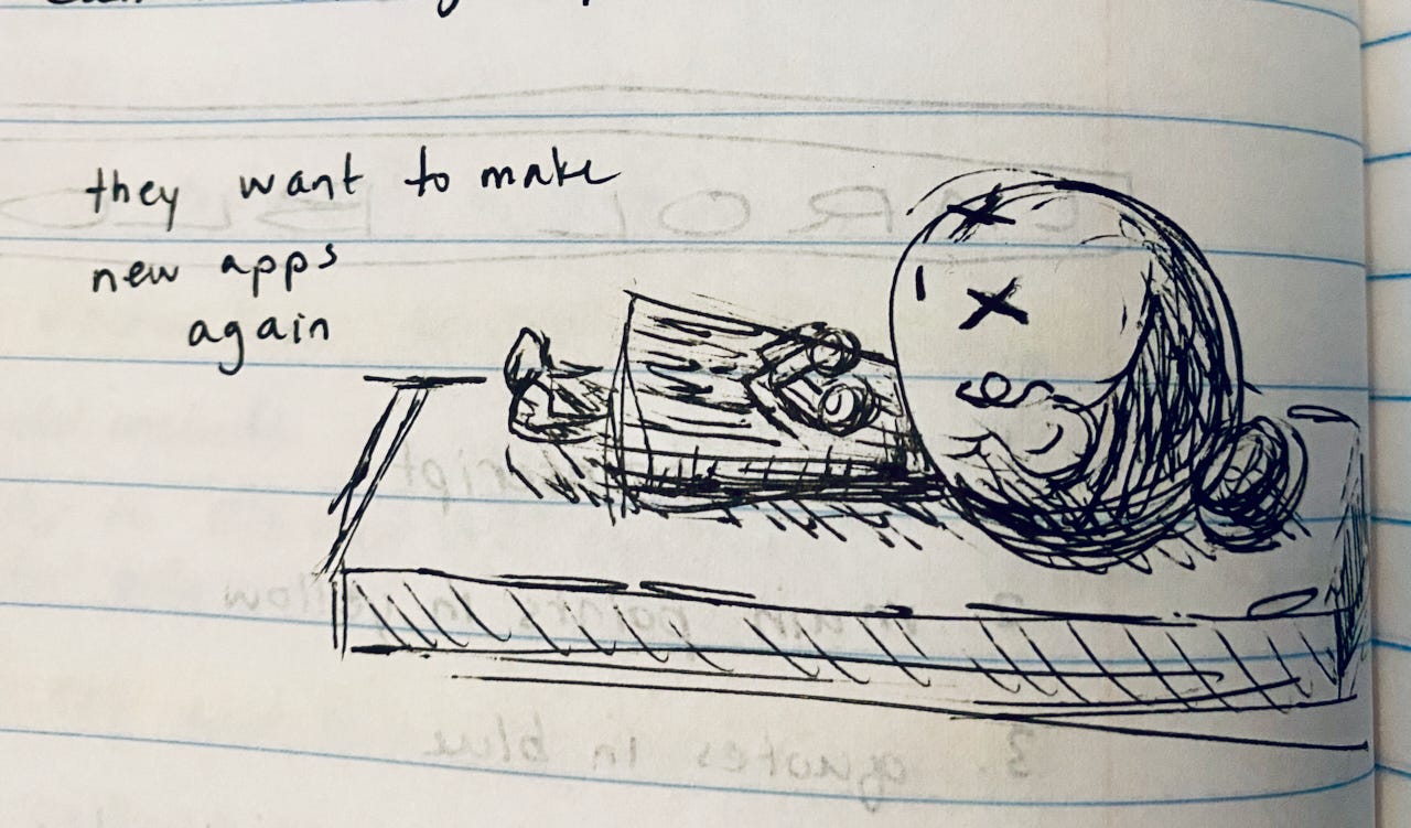 A sketchy ink drawing of a person lying dead on a slab. The person has an oversized head and wears their dark hair in a messy bun. Their eyes are Xs, and their arms are crossed over their chest. A sloppy handwritten note beside the drawing reads “they want to make new apps again”