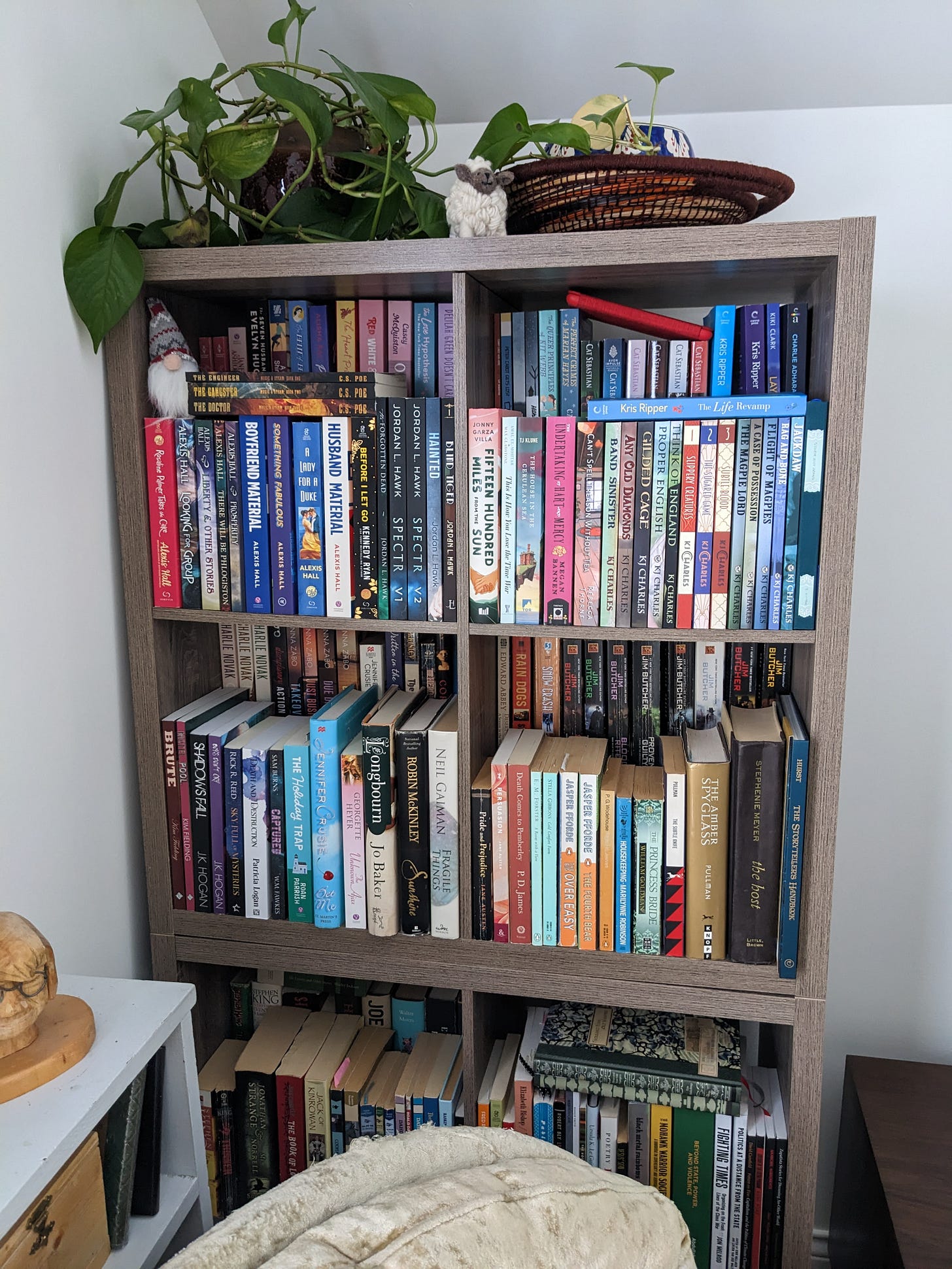 Cube-style shelves full of books, topped with a potted plant and a small cheeky sheep, and a gnome in one corner Cube-style shelves full of books, topped with a potted plant and a small cheeky sheep, and a gnome in one corner