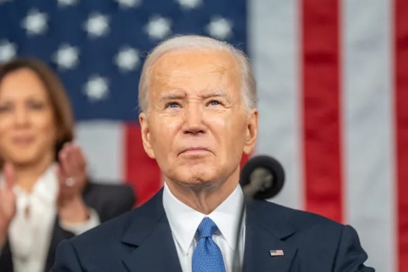 Photograph of Joe Biden standing at a podium with Kamala Harris blurry in the background