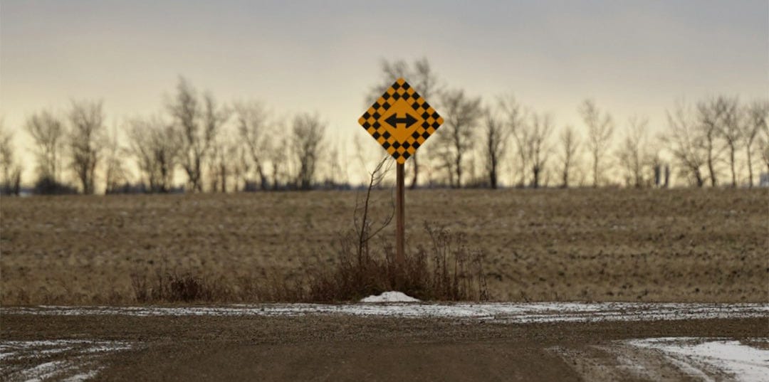 Yellow directional sign at a rural crossroads