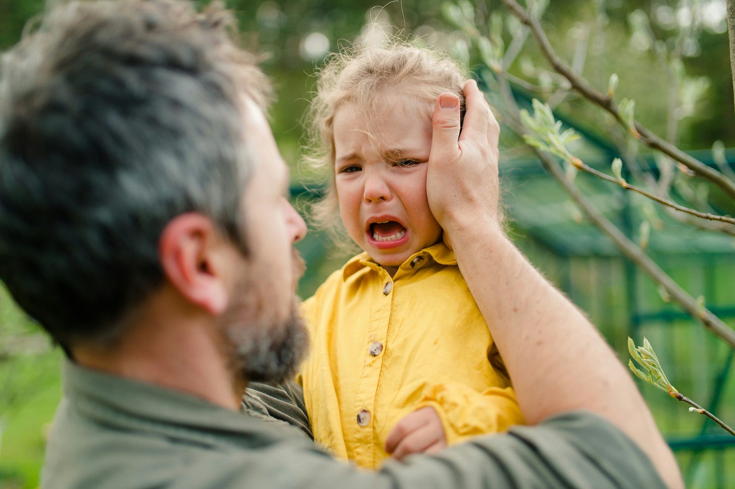 Father comforts crying child.