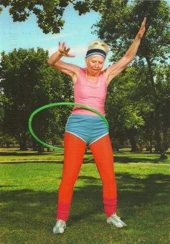 This may contain: an older woman is doing exercises with a hula hoop in the park on a sunny day