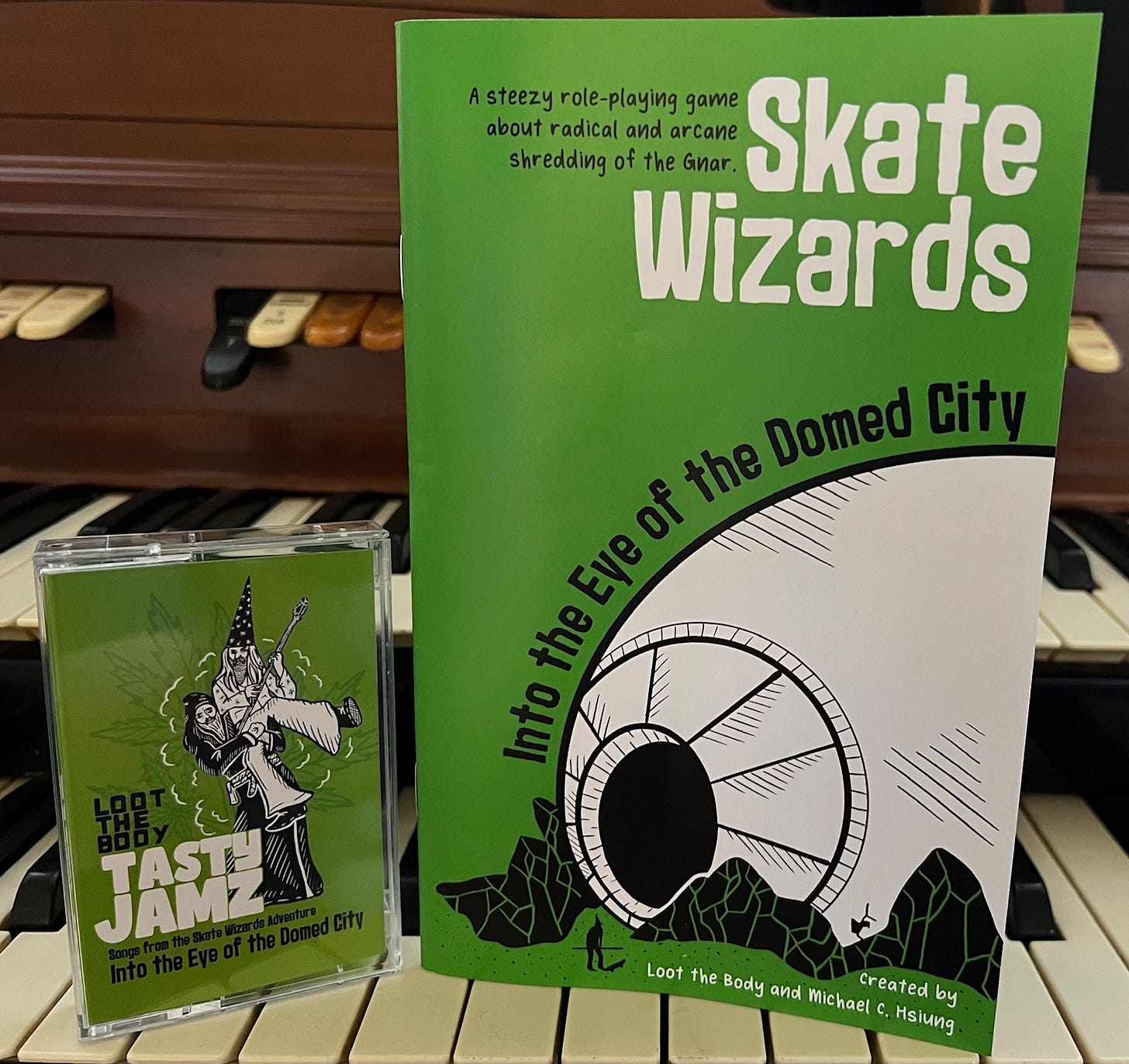 A Loot the Body Tasty Jamz cassette and a Skate Wizards II: Into the Eye of the Domed City zine sitting on top of a vintage organ.
