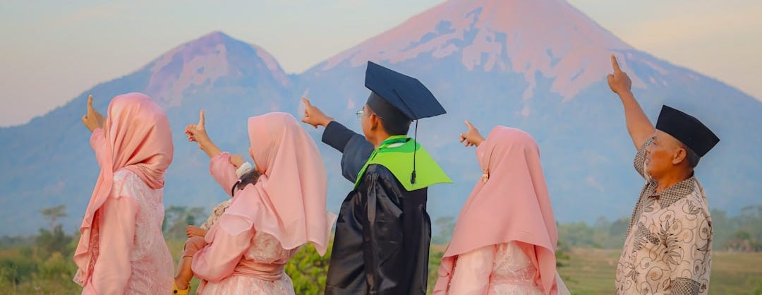 a group of people standing next to each other in front of a mountain a group of people standing next to each other in front of a mountain