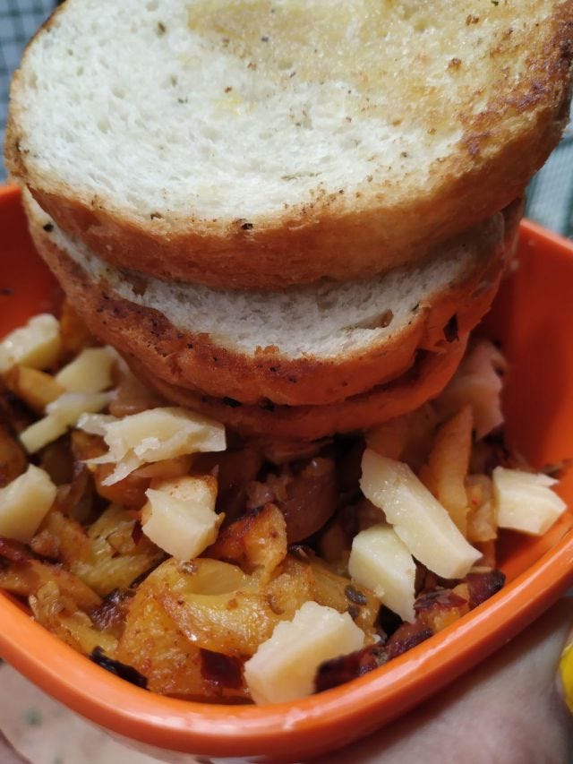 An orange bowl with pineapples, bacon topped with cheese and three slices of bread on the side.