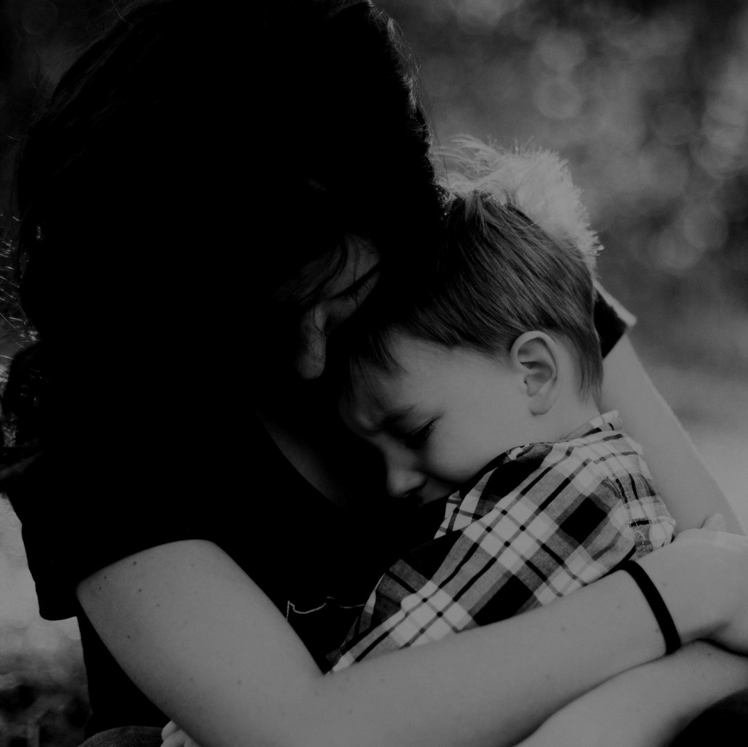 woman hugging boy on her lap