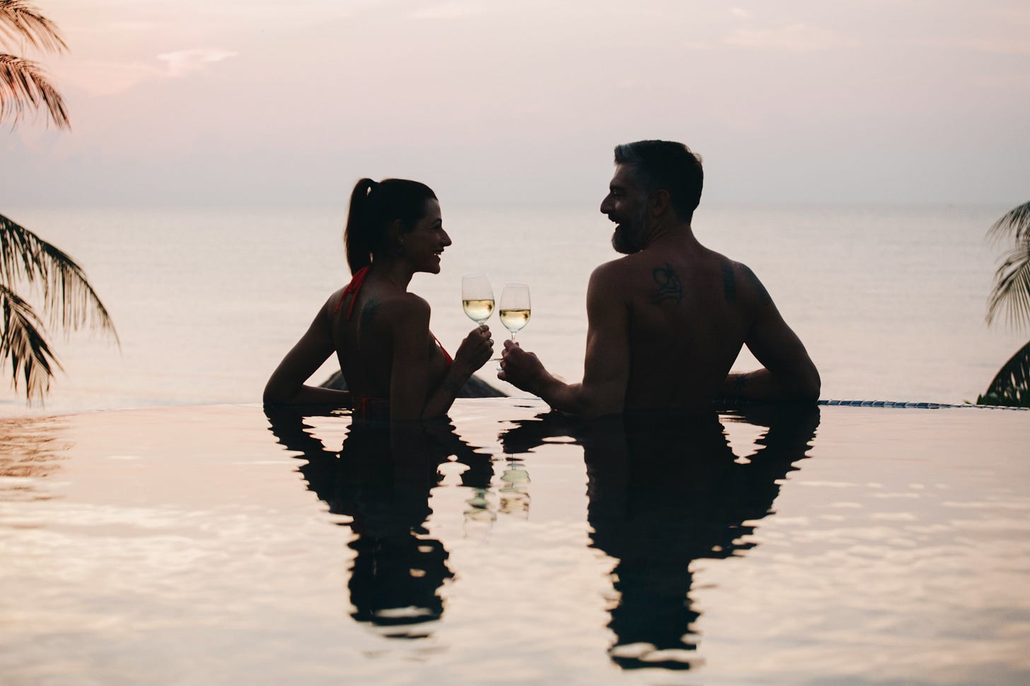 a couple drinking champagne in a swimming pool, silhouetted