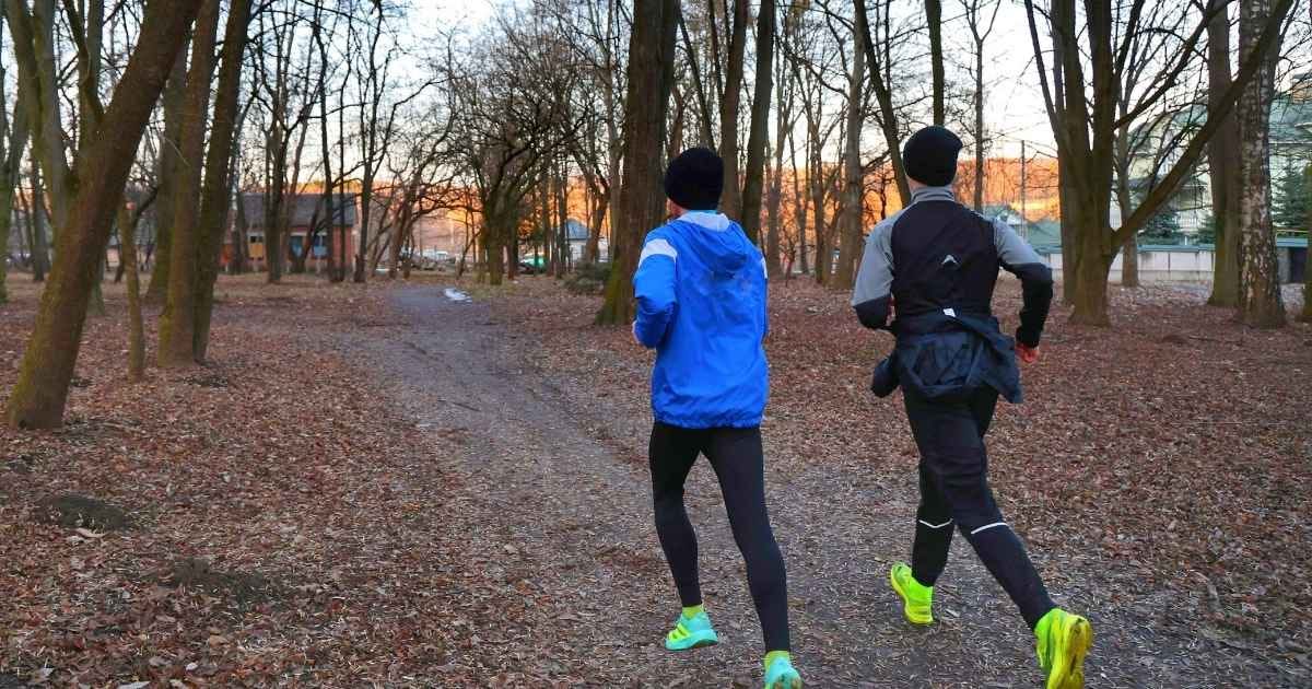 People Running in a Leaf-Covered Park Trail
