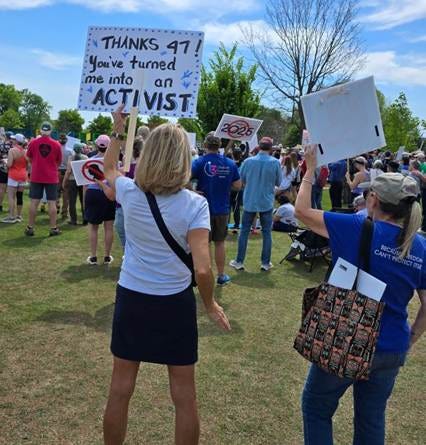 Sporty, blonde woman holds sign, saying,  "Thanks 47, you've turned me into an activist. "