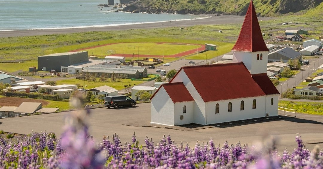 a red and white building with a red roof surrounded by purple flowers a red and white building with a red roof surrounded by purple flowers