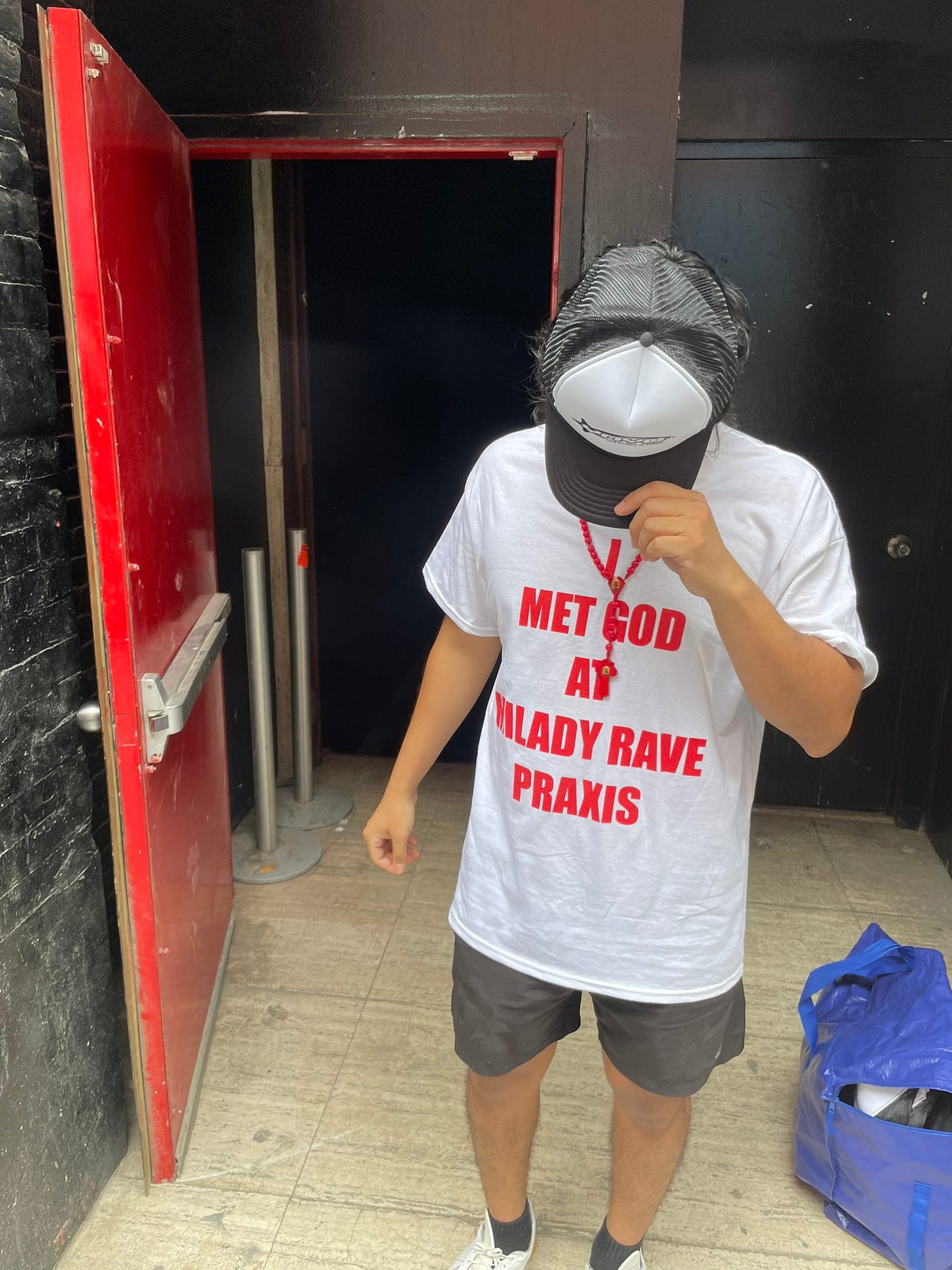 Person in shirt saying "Met God At Milady Rave Praxis" Person in shirt saying "Met God At Milady Rave Praxis"