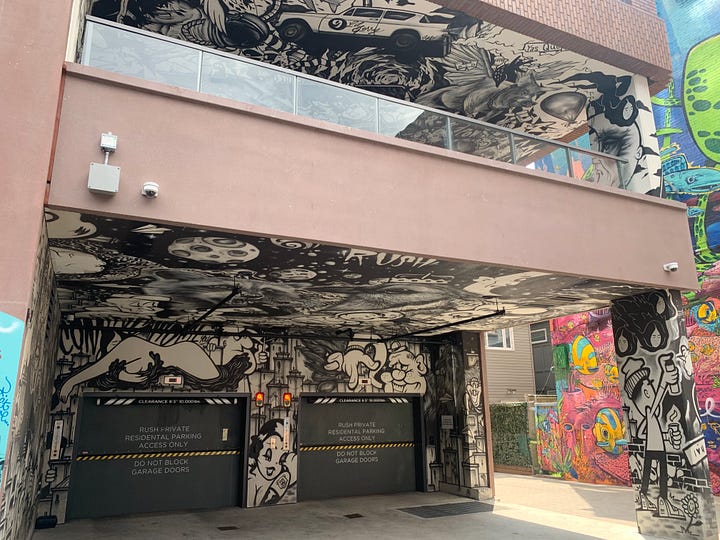 A loading garage with walls and two floors of ceilings covered in black and white mural art.