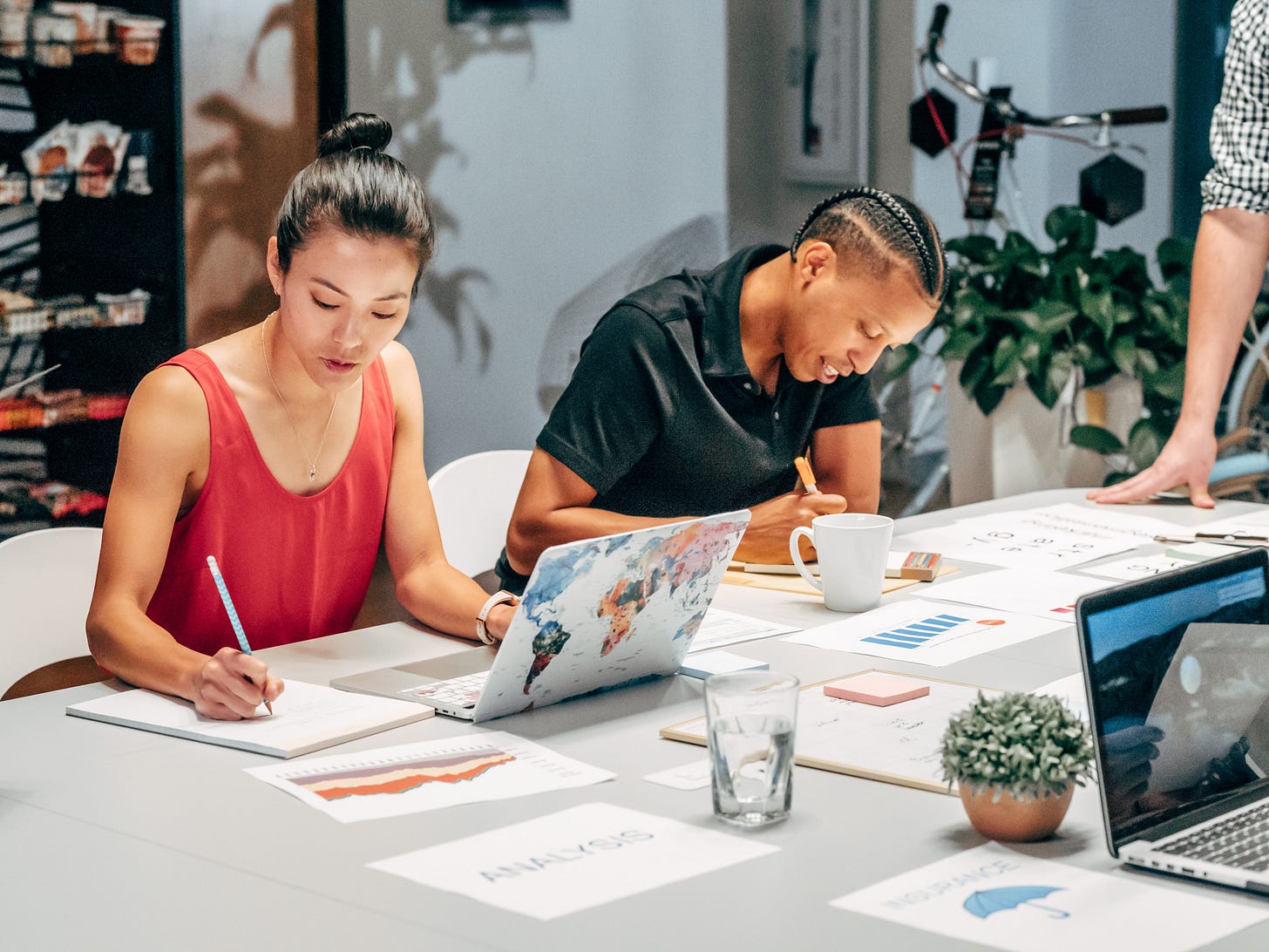 An Asian woman writes beside a black man. An Asian woman writes beside a black man.