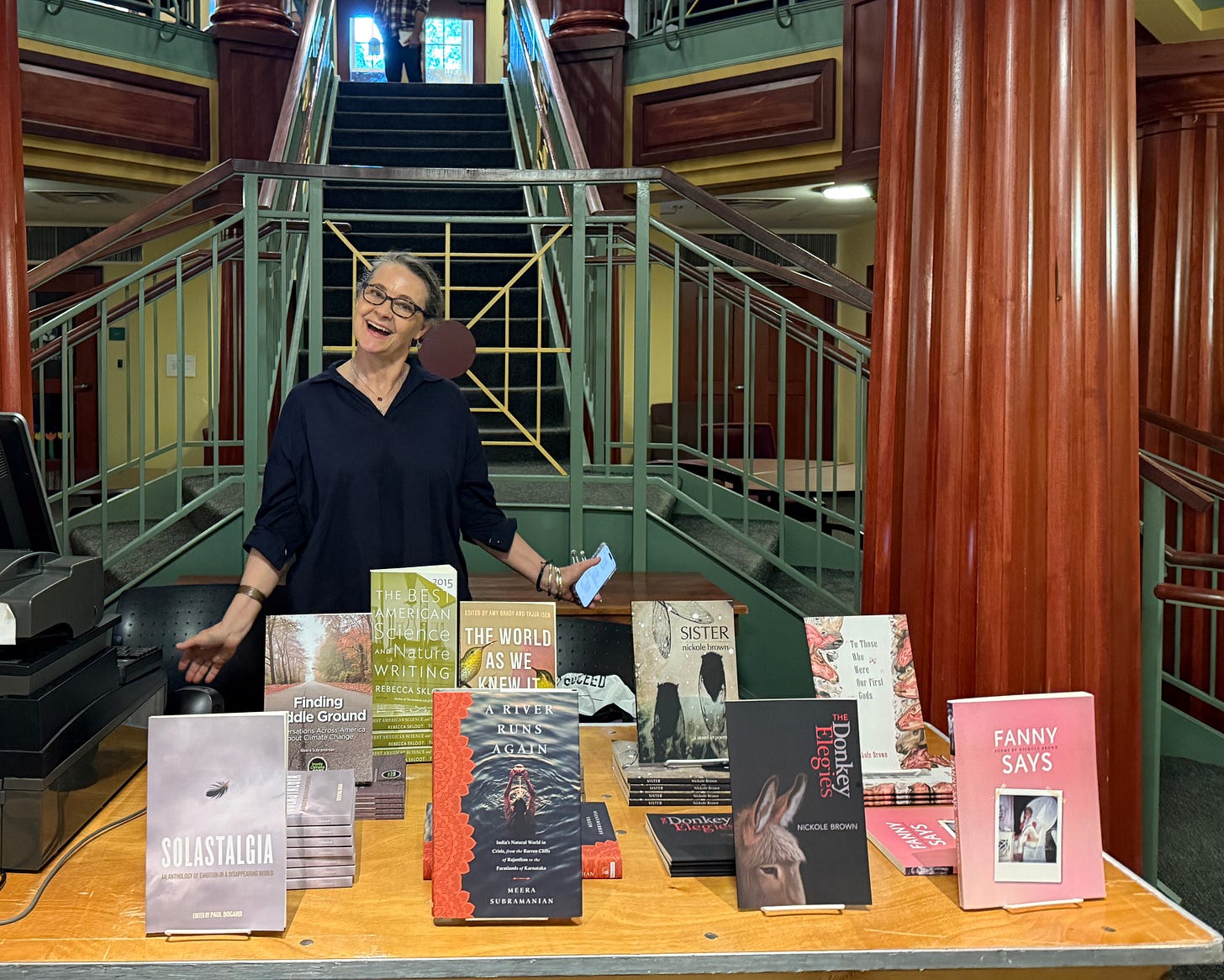 Woman smiling behind a table full of books