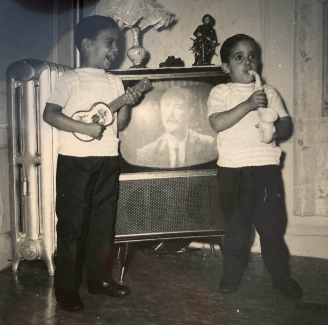 Two small kiddos play a toy guitar and toy saxophone in front of a television. They look happy and silly. The photo is black and white. Two small kiddos play a toy guitar and toy saxophone in front of a television. They look happy and silly. The photo is black and white.