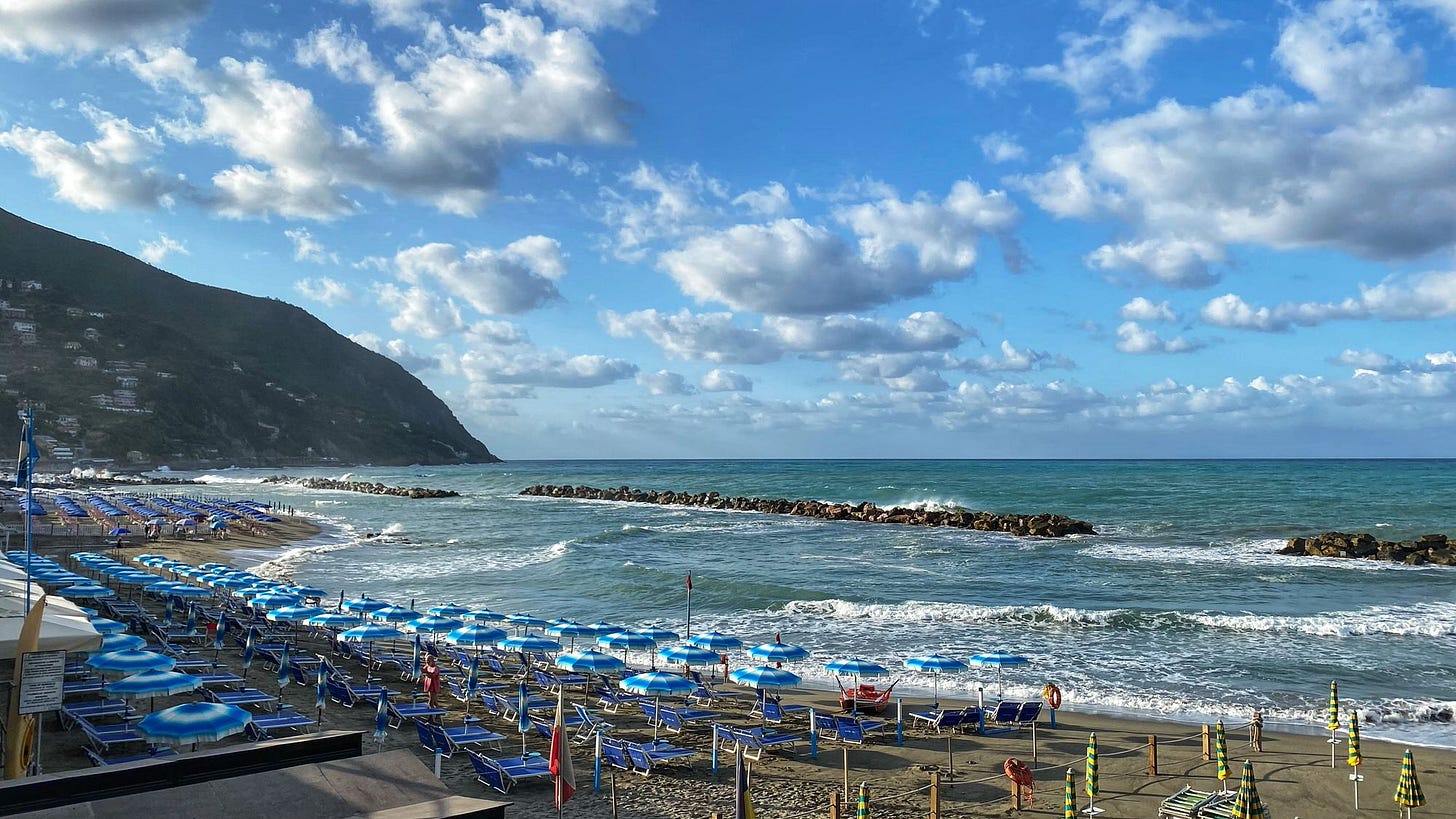 Image of umbrellas and chairs neatly arranged on a beach in Italy.