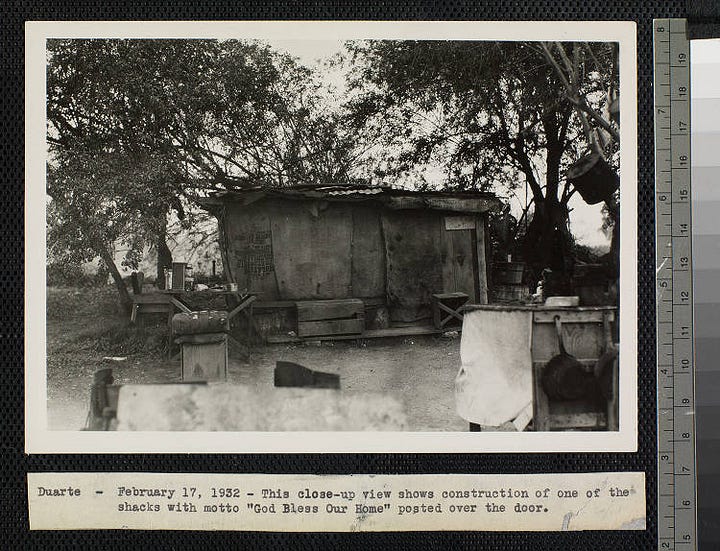 Description A view of a shack with a wooden frame and door, burlap sides, and a corrugated sheet metal roof. There are boxes and a seat outside of the hut, and roughhewn tables with tins and cans on them and pots hanging off the sides of them. One of the burlap sides was previously a sack for "Molasses red beet pulp". Description A view of a group of shacks on a lot in the Graham neighborhood of Los Angeles. Some of the huts are made with corrugated metal and wood, while others appear to be tents. A hand-painted sign reading "Hoover Town" is attached to a telephone pole in the foreground. There are a few people and a dog standing in the center of the lot and a car and truck parked on the right. There are permanent houses on the left and in the background.