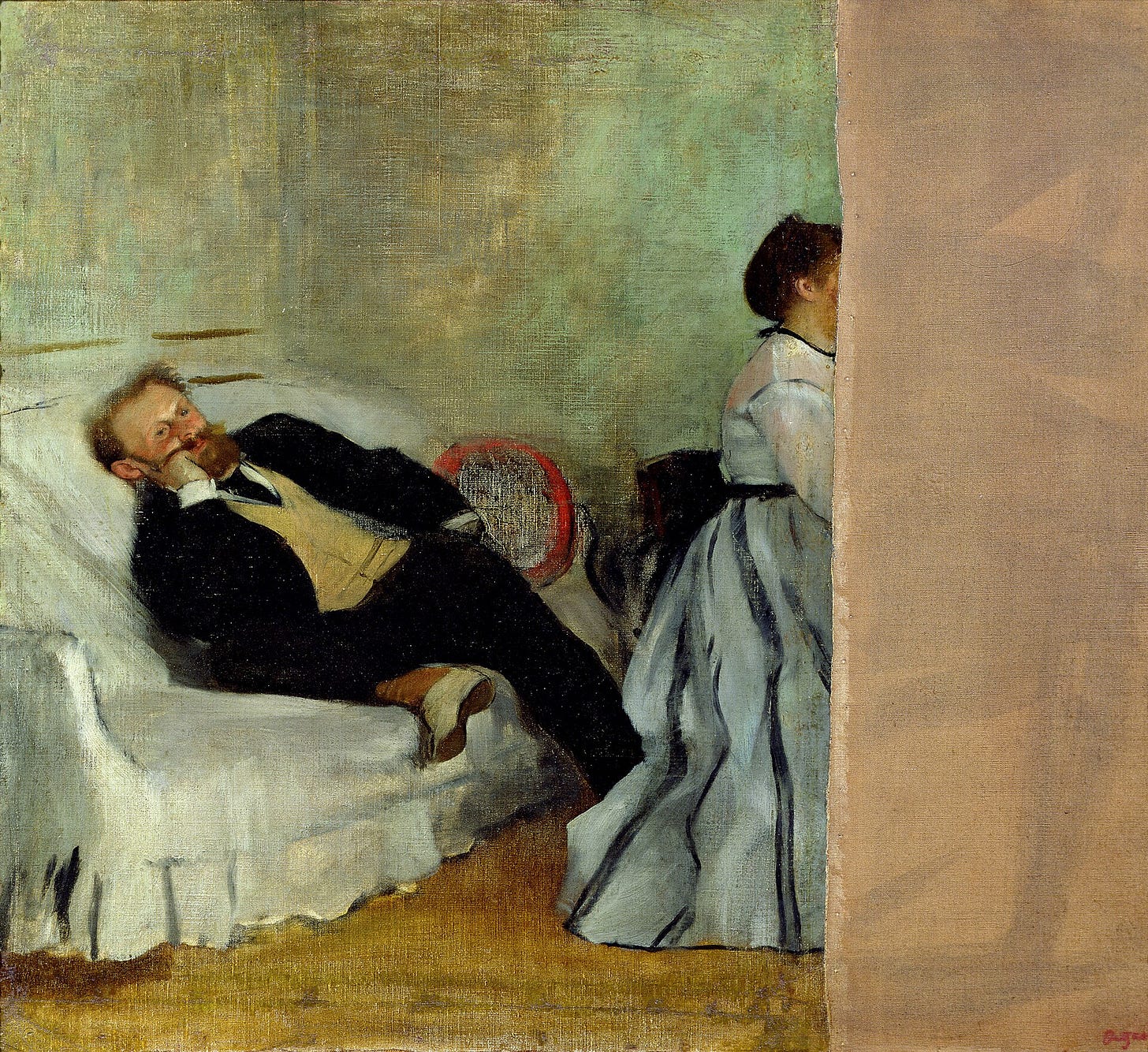A bearded man in a dark suit reclines on a sofa, one hand under his head, beside the edge of a piano. On the right, where a woman sat at the keyboard, the canvas stops at a blank vertical strip.