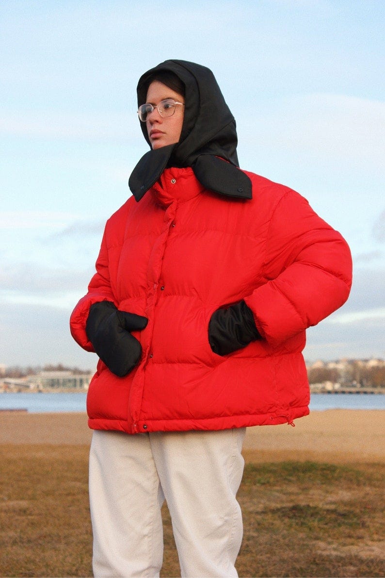 May include: A red puffer jacket with a black hood and black gloves.