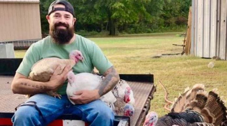 Picture of Aaron Spencer holding turkeys on a farm
