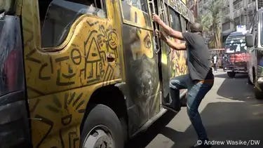 A man in Nairobi grabs the side of a matutu minibus 