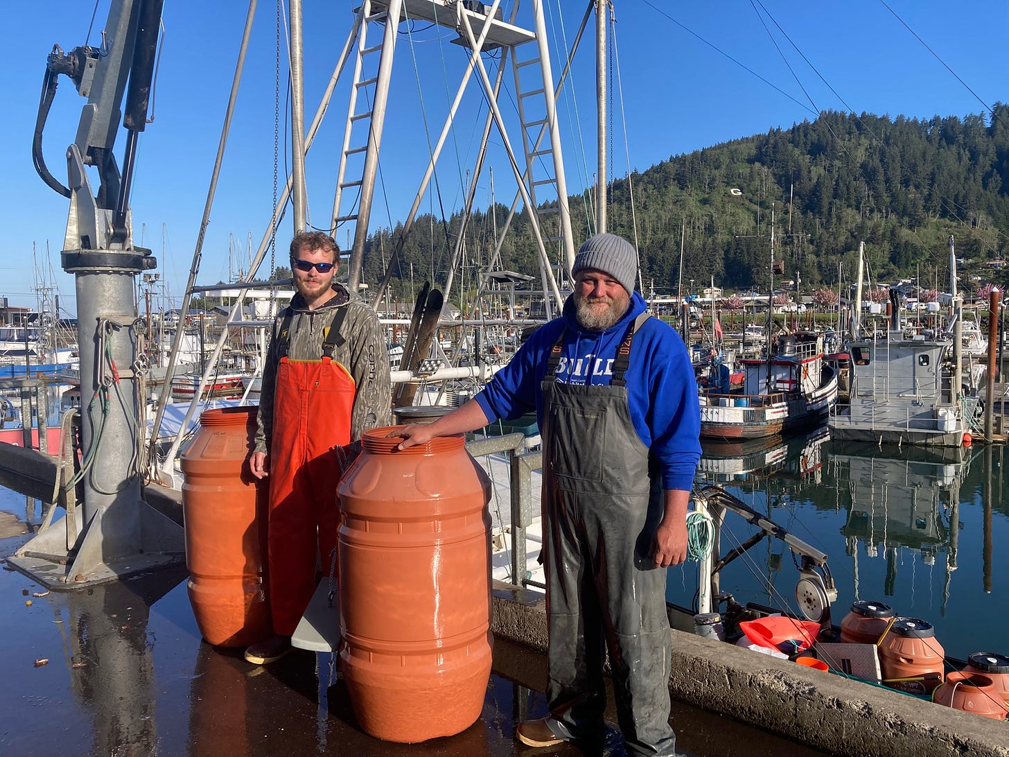 Nedian deckhand Joe Bentley, left, and Capt.Hank Slavens stand with salmon barrels after they unloaded their catch in Garibaldi, Ore. on April 29, 2026.