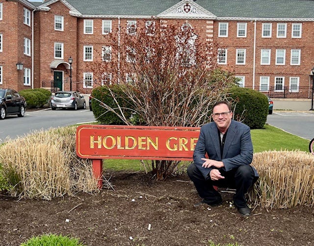 A person squatting in front of a sign

Description automatically generated