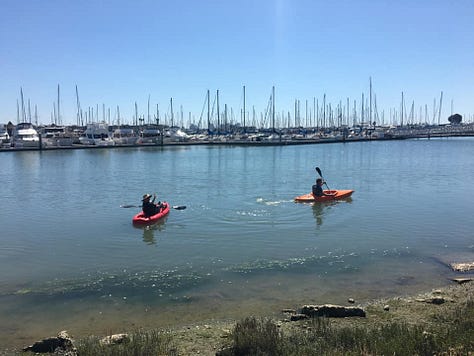 Red kayak in river, orange kayak tip, two kayers, yellow Malibu Two kayak