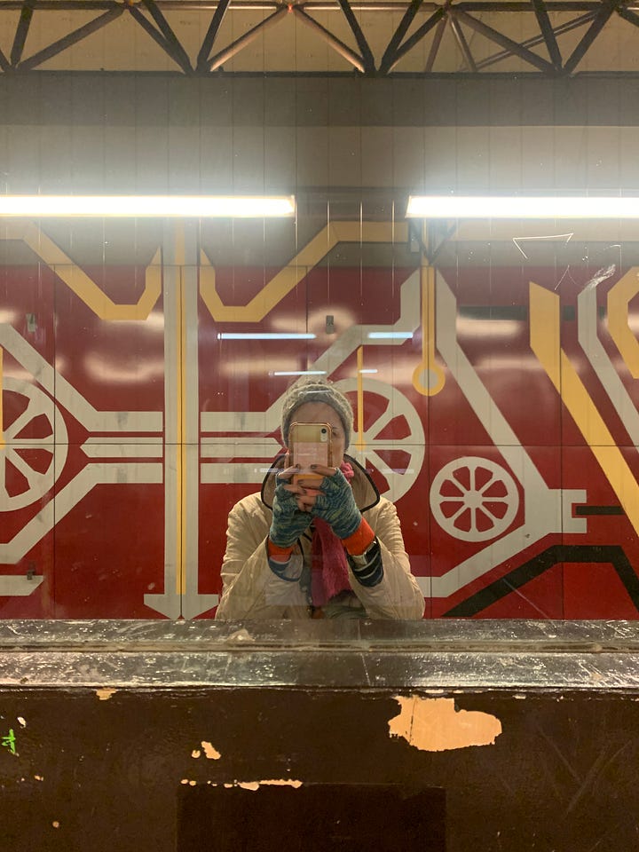 two photos: on left, author dressed warmly taking selfie in mirror with colorful decorative wall behind her R) the UBhahn station of Rohrdamm with red, yellow swirls