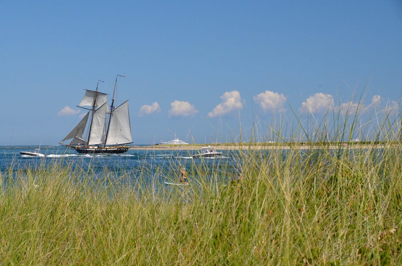 A sailing boat on the sea near the sandy shores of Nantucket island