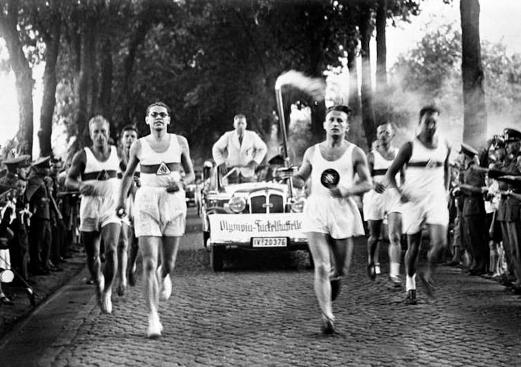 Black and white photo of runners carrying the Olympic torch Black and white photo of runners carrying the Olympic torch