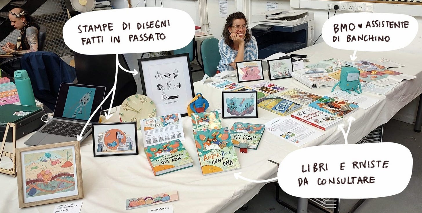 foto di claudia dietro a un banchino su cui sono esposti disegni e libri