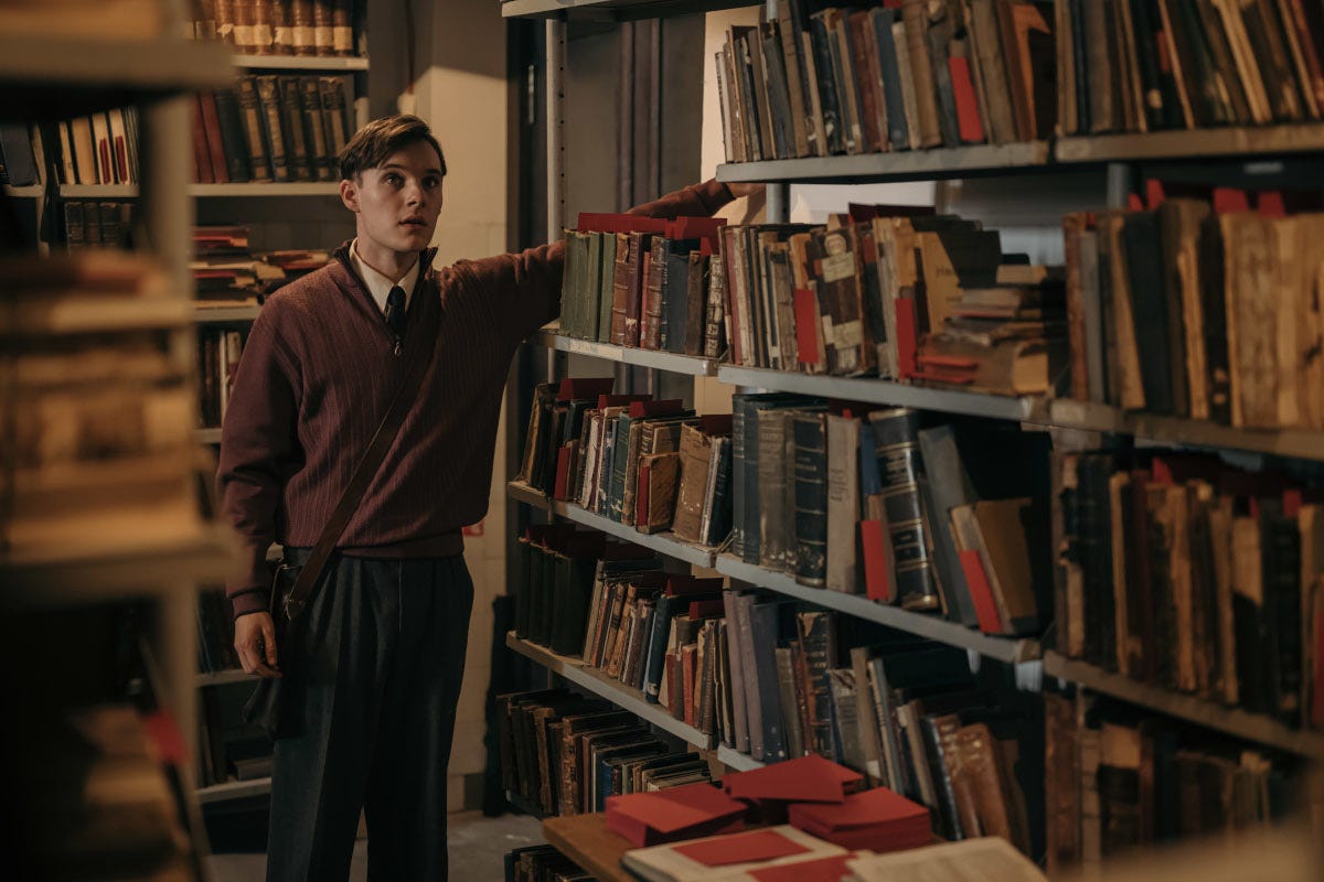Teenage boy standing next to shelves of books Teenage boy standing next to shelves of books