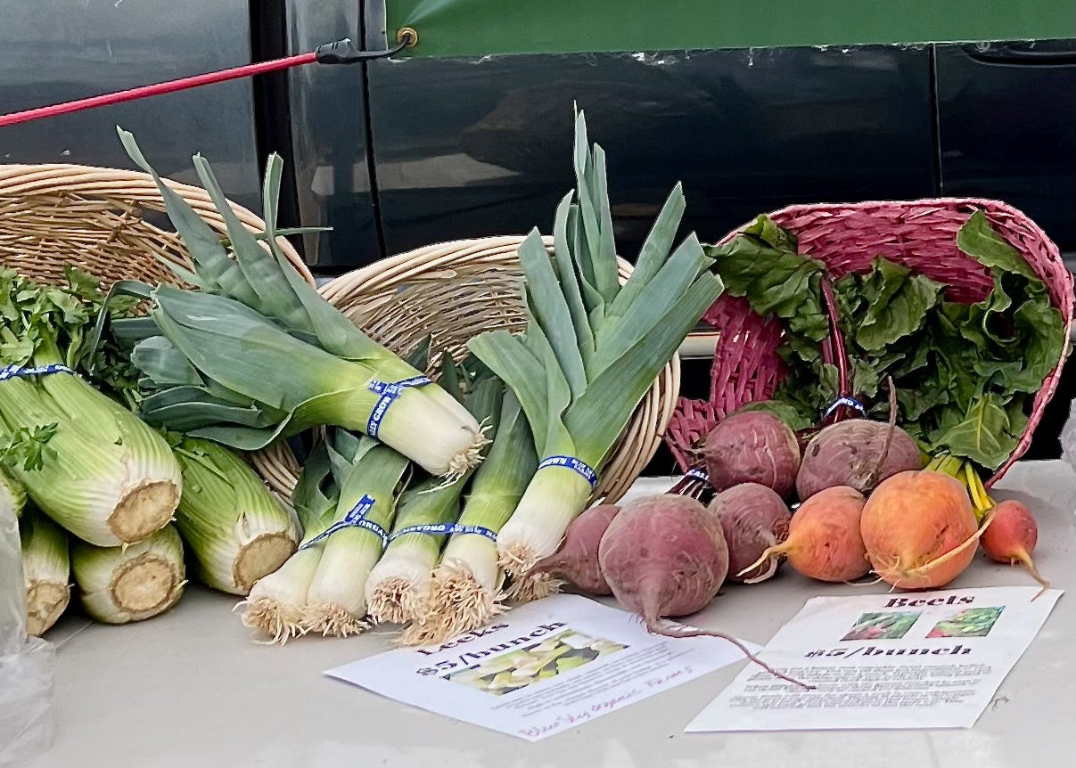 a table with celery, leeks, and beets in baskets