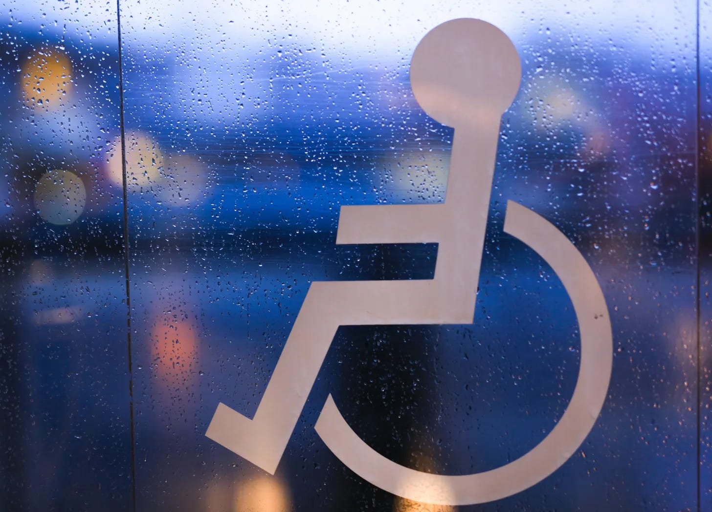 Wheelchair symbol sticker on a window covered in raindrops
