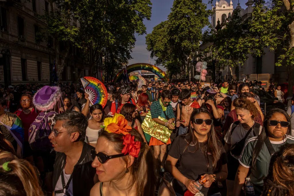 People marching on a street, some wearing colorful outfits.