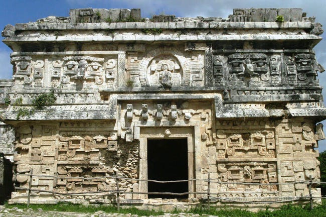 Temple maya vu de face, ressemblant vaguement àn une église avec ses bas-reliefs et sa sculpture de figure divine au-dessus de l'entrée Temple maya vu de face, ressemblant vaguement àn une église avec ses bas-reliefs et sa sculpture de figure divine au-dessus de l'entrée