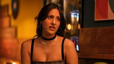 A young woman in a strappy black top is looking off to her left. The image has an orange hue.