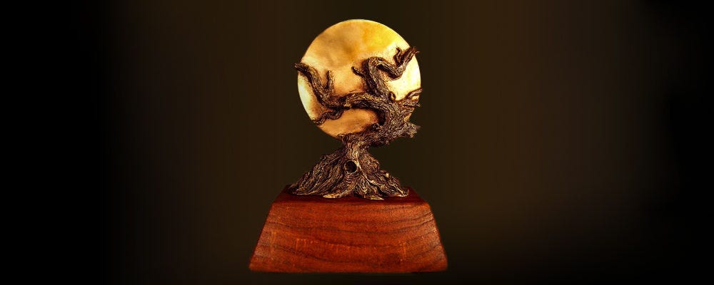 The World Fantasy Award against a brown gradient background. The award features the winding trunk of a tree in front of a full moon.