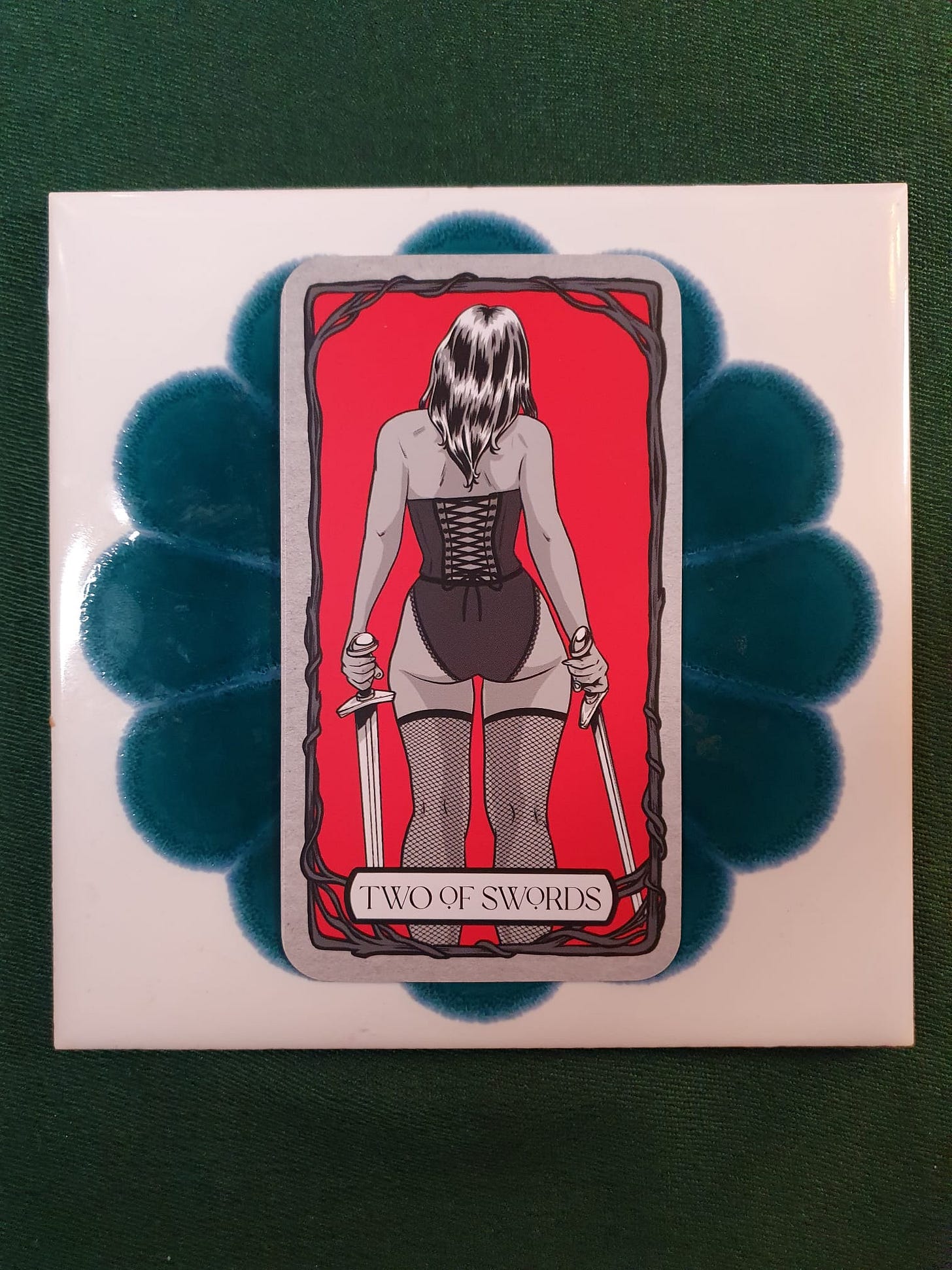 Two of Swords tarot card from Elizabeth Sulis Kim’s Tarot DMs reading, showing a figure holding two swords against a red background. Two of Swords tarot card from Elizabeth Sulis Kim’s Tarot DMs reading, showing a figure holding two swords against a red background.