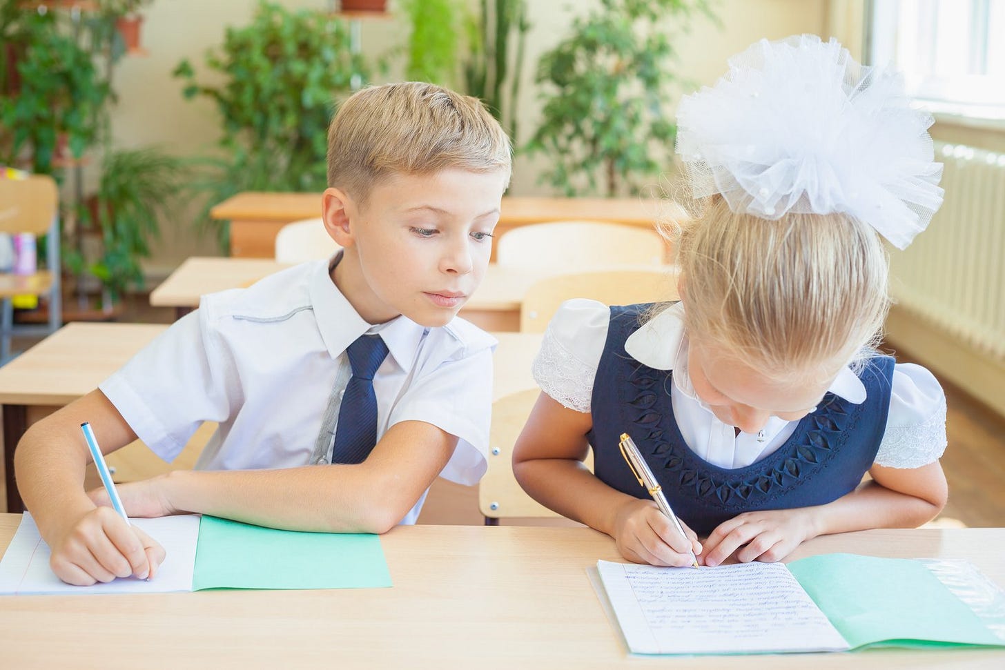 A schoolboy leans over to copy a girl's written answers A schoolboy leans over to copy a girl's written answers