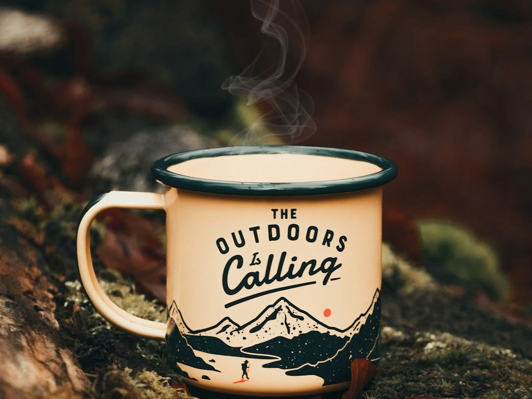 a cup of coffee sitting on top of a tree trunk a cup of coffee sitting on top of a tree trunk